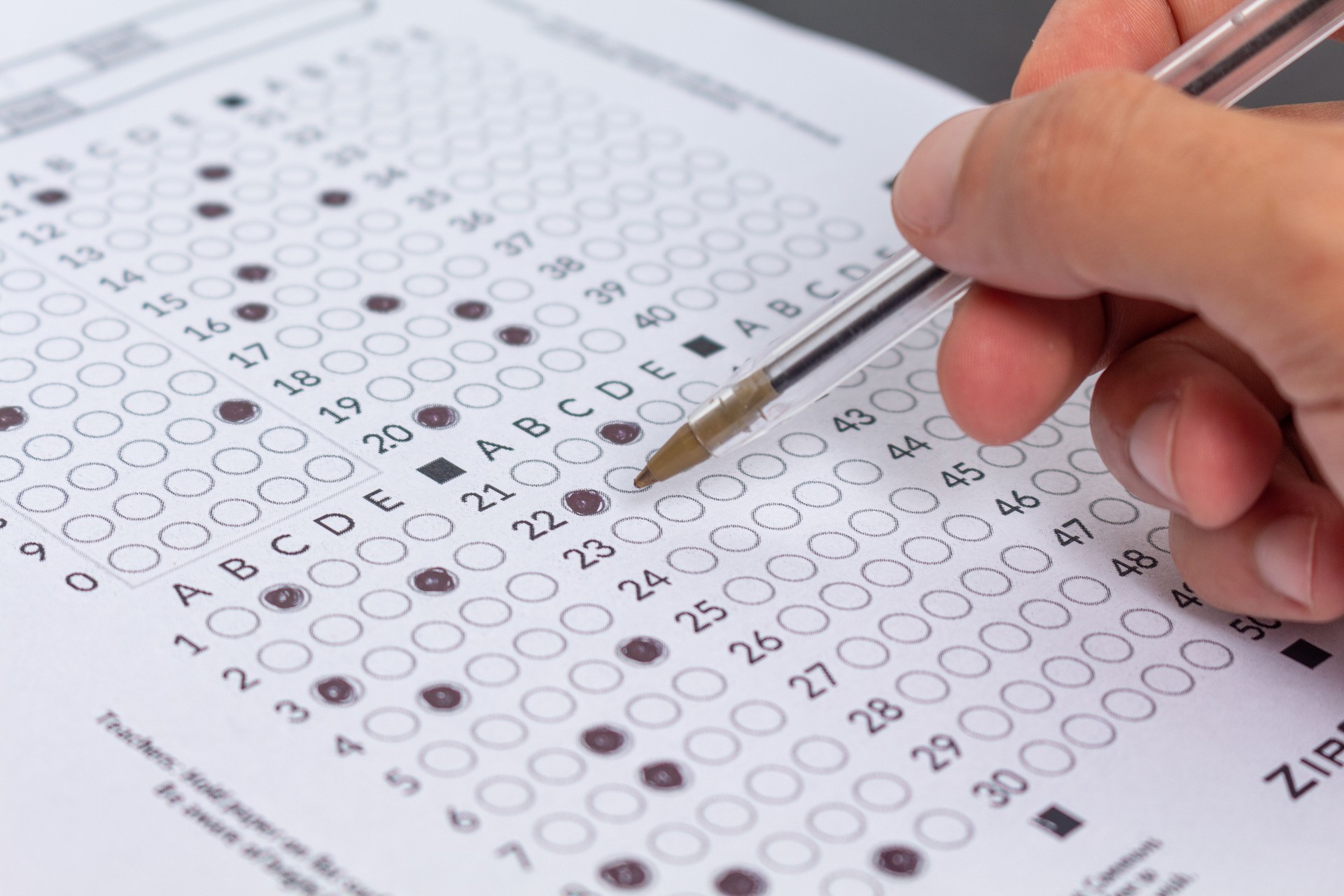 Person filling out an exam answer sheet with a pen, concept for public exams and entrance exams.